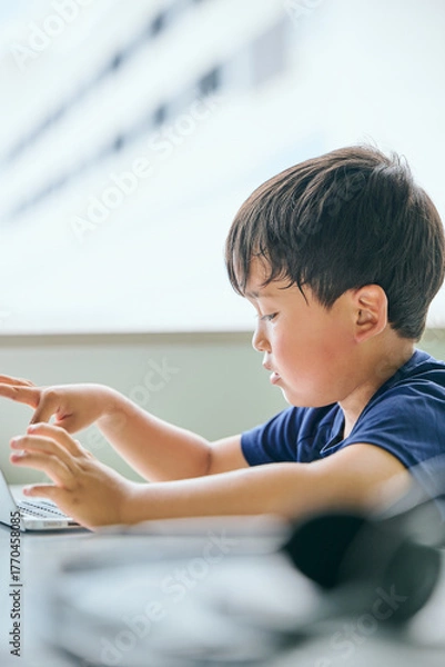 Fototapeta ノートパソコンでオンライン学習をする小学生の男の子