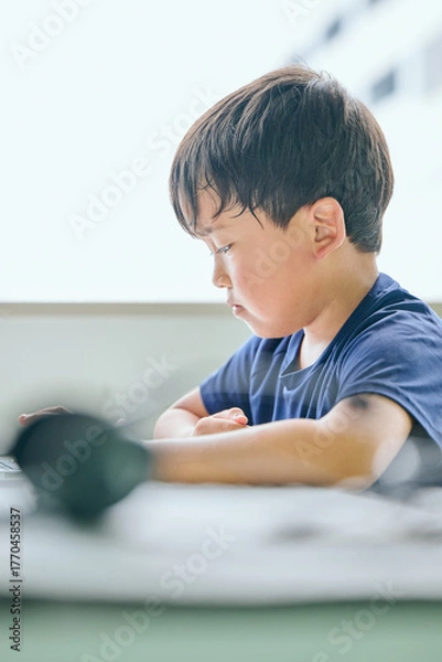 Fototapeta ノートパソコンでオンライン学習をする小学生の男の子