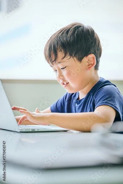 Fototapeta ノートパソコンでオンライン学習をする小学生の男の子