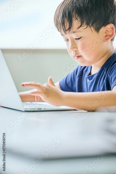 Fototapeta ノートパソコンでオンライン学習をする小学生の男の子