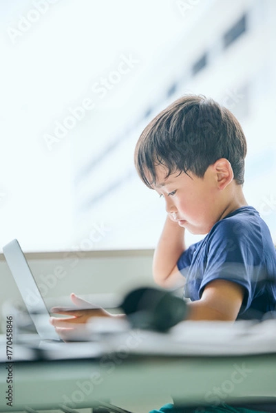 Fototapeta ノートパソコンでオンライン学習をする小学生の男の子