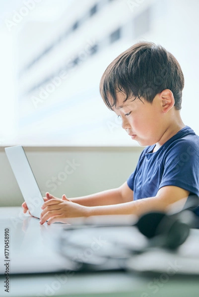 Fototapeta ノートパソコンでオンライン学習をする小学生の男の子
