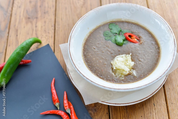 Fototapeta Mushroom cream soup in a white plate on a wooden table