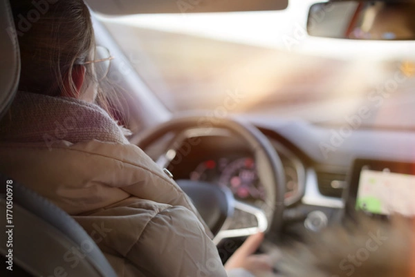Fototapeta Young girl drives a car on the highway in the afternoon sun.