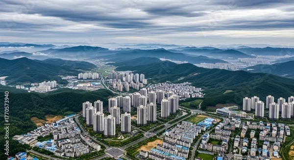 Fototapeta Apartment complex in green hillsides under a cloudy sky cityscape