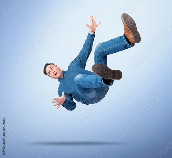 Obraz Surprised man in casual clothes falling down with arms spread, on blue gradient background, concept of failure, accident, shock, losing balance, or business risk