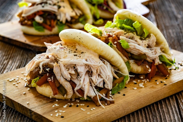 Fototapeta Bao Buns with pulled chicken and vegetables on wooden table	