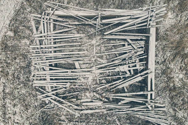 Fototapeta Aerial view of an abandoned wooden building against the backdrop of snow in winter. Abandoned barn close-up from above