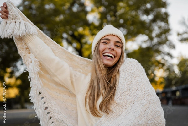 Obraz attractive smiling young blond woman walking in winter park having fun in warm white knitted sweater, cape and hat, cold season