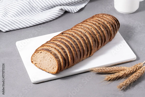 Fototapeta Sliced rye bread on cutting board. Whole grain rye bread