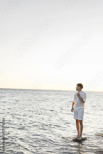 Fototapeta An Individual Deep in Thought While Gazing at the Ocean During a Beautiful Sunrise
