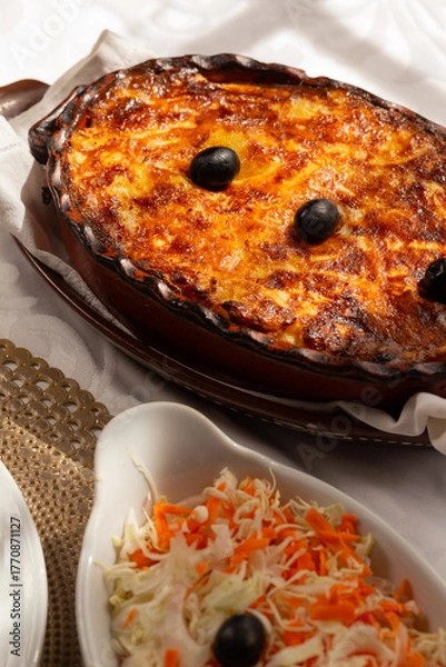 Fototapeta The "Bacalhau com Natas", a traditional Portuguese oven-baked codfish dish made with flaked cod, potatoes and onions, baked until golden and creamy, and often topped with black olives.