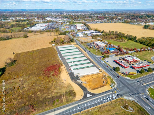 Fototapeta retail buildings and stores along the road with farmland in view. Aerial drone view. 