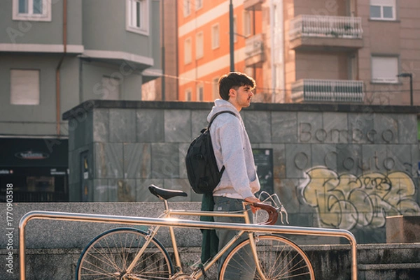 Fototapeta young man or student on the street with vintage bicycle at sunset