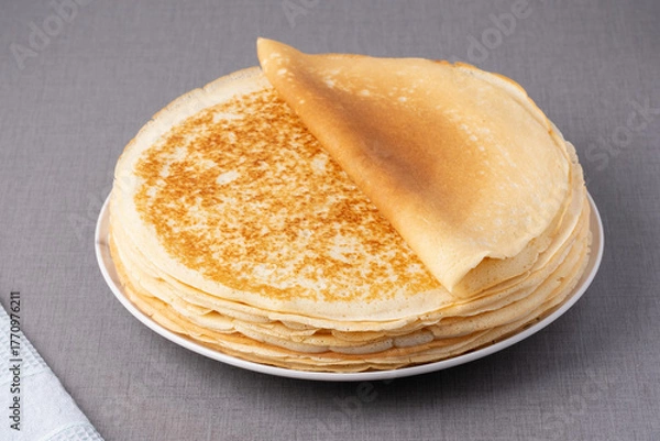 Fototapeta Thin pancakes on a wood table. Homemade crepes, tasty food. Staple of yeast pancakes, traditional for Russian pancake week (Shrove tide). Thin pancake with crispy crust