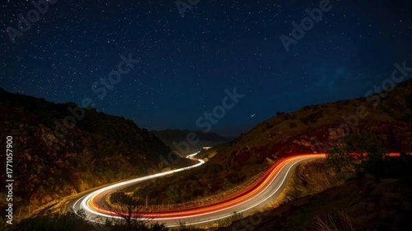 Obraz Night road with light streaks illuminating hills under starfilled sky suitable for travel and landscape visuals, brochures, and websites.