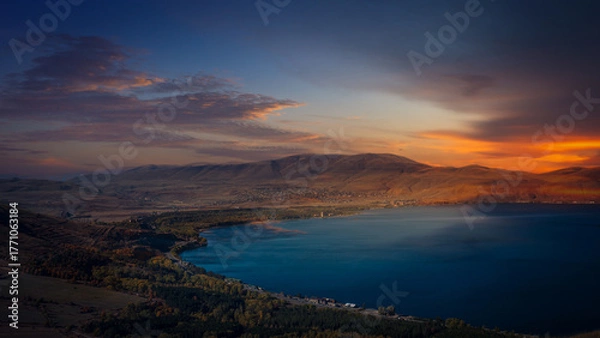 Fototapeta Serene evening scene over Lake Sevan surrounded by mountains, with warm colors of sunset reflecting on the tranquil surface.
