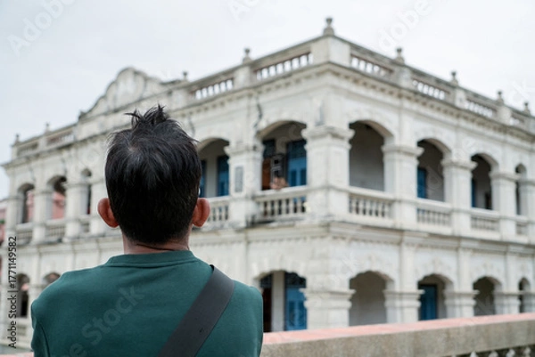 Fototapeta Tourist looking at a Western-style building in Taiwan. Back view, travelling, learning local history. Blur background.