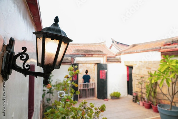 Fototapeta Street lamp in front of a blur Fujian-style house courtyard. Focus on the lamp.