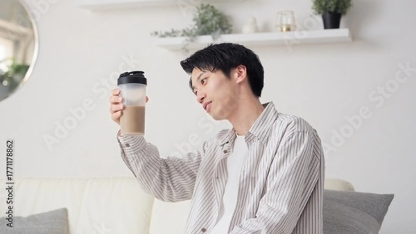 Obraz リビングでプロテインを見るアジア人男性