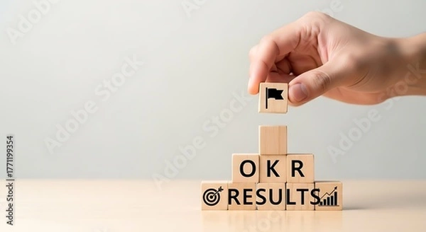 Fototapeta Businessman's hand completing a wooden block structure symbolizing the achievement of objectives and key results