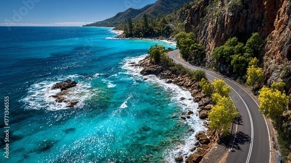 Fototapeta Scenic coastal highway winds alongside intensely blue ocean waters next to rugged cliffs