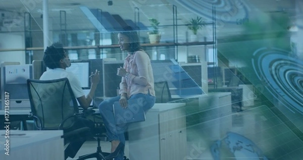 Fototapeta Discussing project man and woman wearing business casual in office, with AR schematics on monitors