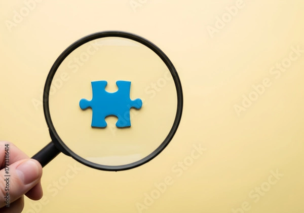 Fototapeta Magnifying glass focusing on blue puzzle on light yellow surface, concept of discovery, teamwork, problem solving, analysis, creative idea