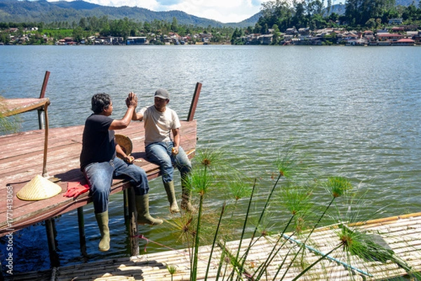 Fototapeta Friends Celebrate Fishing Success With High Five at Scenic Lake