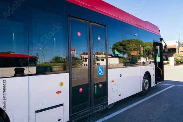 Fototapeta Modern city bus parking on a street, showing reflections on large windows and a disabled access symbol on the door