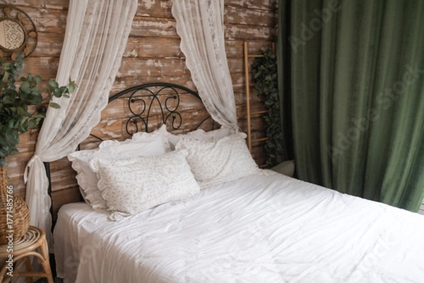 Obraz Details of bright elegant interior in cozy bedroom. Wicker side table with vase and flowers next to comfortable bed with white linen bedding. 