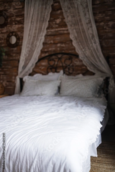 Obraz Details of bright elegant interior in cozy bedroom. Wicker side table with vase and flowers next to comfortable bed with white linen bedding. 