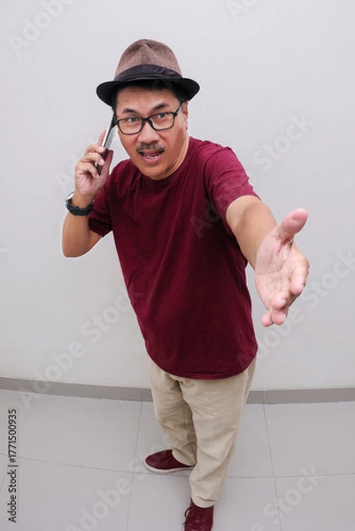 Fototapeta man standing with welcoming arm while talking on the phone