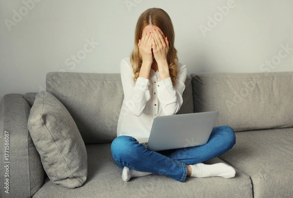 Fototapeta Sad overworked woman suffering from headache, stress, migraine while working with laptop at home
