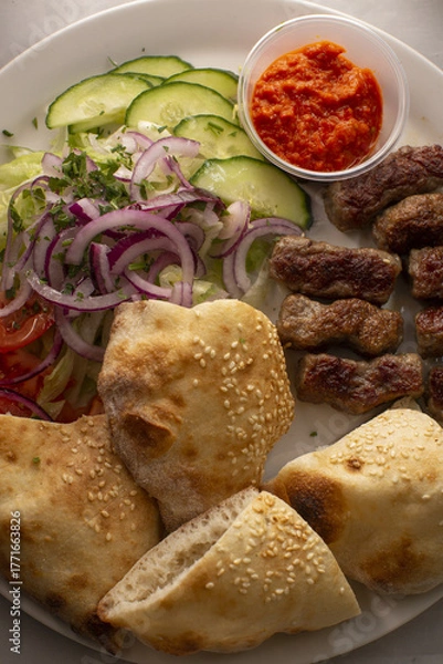Fototapeta Casual meal with flavorful bites, Rustic platter serving grilled meats and fresh sides, Delicious assortment of grilled meats with crisp vegetables and sauces