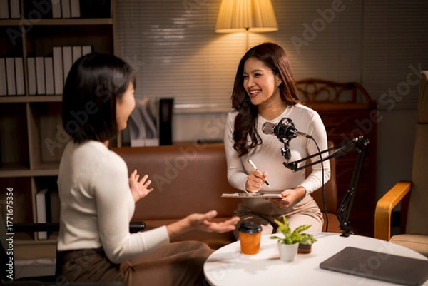 Obraz Two asian women recording a podcast and having a conversation