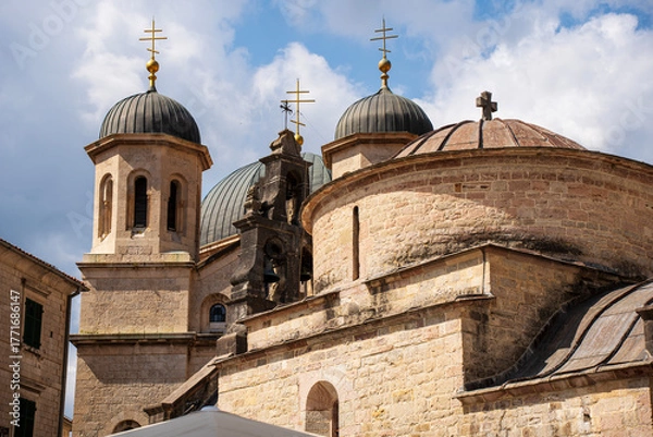 Fototapeta The domes and bell towers of the Orthodox Church of St. Nicholas rise above Kotor Old Town under a bright sky, showcasing its Byzantine architecture.