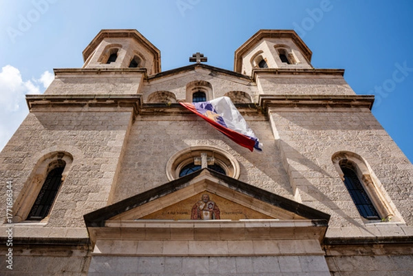 Fototapeta The domes and bell towers of the Orthodox Church of St. Nicholas rise above Kotor Old Town under a bright sky, showcasing its Byzantine architecture.