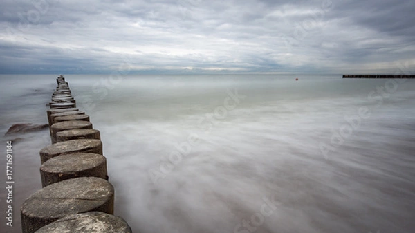 Obraz boulders and wooden breakwaters on the beach
