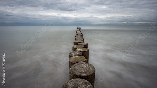 Obraz boulders and wooden breakwaters on the beach
