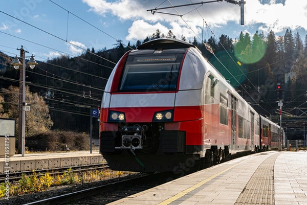 Fototapeta Modern Red and White Passenger Train at Railway Station in Mountain Landscape