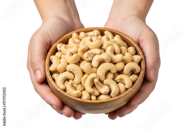 Fototapeta Hands holding a wooden bowl full of cashews
