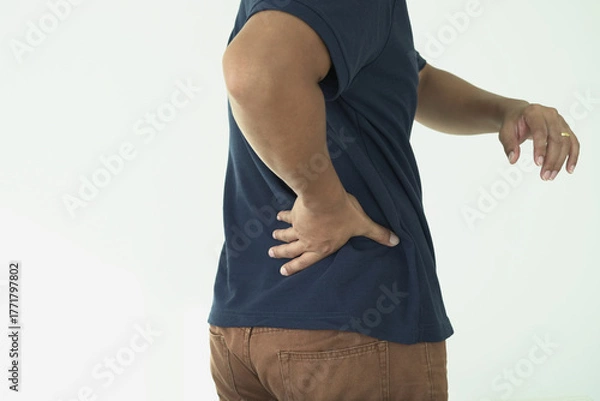 Fototapeta An asian businessman overworks and feels pain in his back from using a laptop, hand holding and rubbing hurt area, numbness in the waist area and back and a kind of health care and medical concept.	
