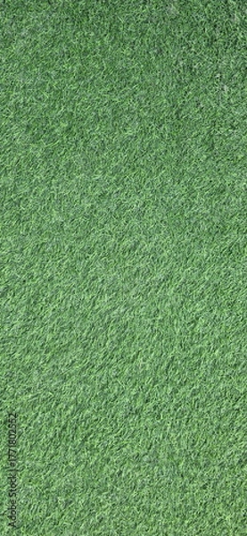Fototapeta Vertical image of Artificial green grass background. Artificial turf made from synthetic fibers, two types of plastic,  (PE),  (PP). Surface of green synthetic fibers looks like natural grass.
