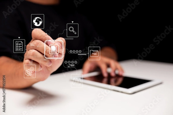 Fototapeta A person interacts with digital icons on a tablet, illustrating technology and innovation in a modern workspace.