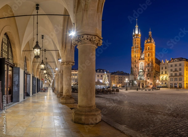 Fototapeta St Mary's church on snow covered Main Square in winter Krakow, Poland, illuminated in the night, with Cloth Hall arcades