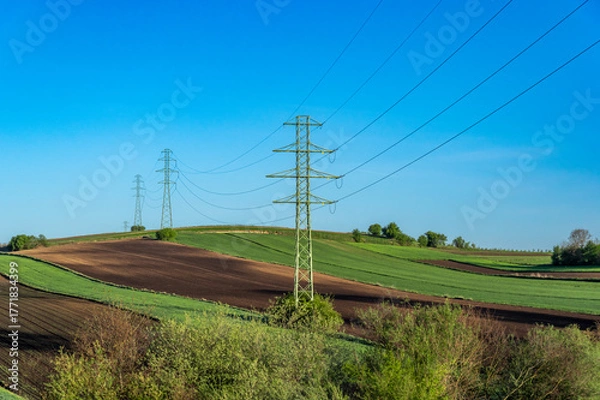 Fototapeta Overhead power line with conductors suspended by towers, rural area of Ponidzie, Poland