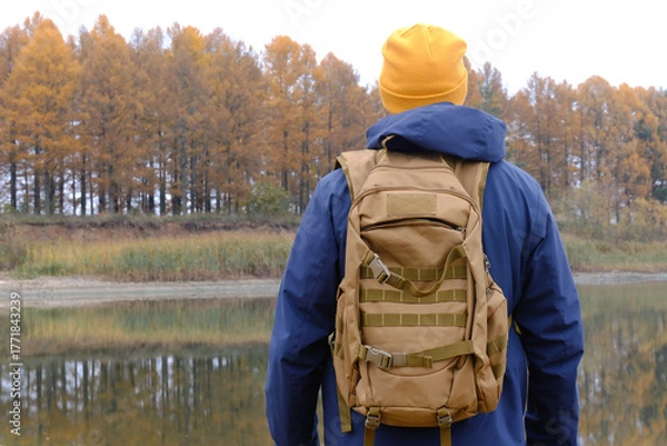 Fototapeta Man backpacking exploring autumn nature by lake