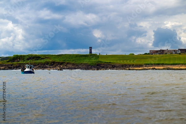 Fototapeta 2023-07-19 A GOLF COURSE AND SHORELINE IN ANSTRUTHER SCOTLAND WITH LUSH GREENS AND A STORMY SKY NEAR THE NORTH SEA