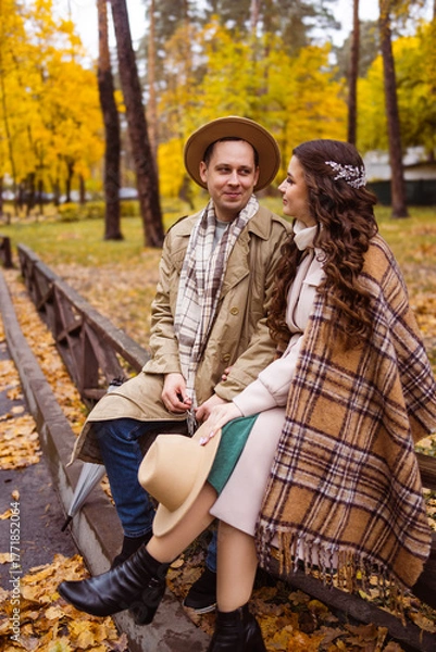 Obraz Charming couple enjoying a cozy moment outdoors in a city park during autumn. They share a joyful smile, conveying warmth and connection on a sunny day.